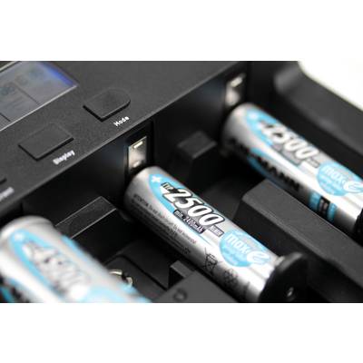 Gros plan sur un chargeur de batteries avec quatre batteries rechargeables. Une batterie est en cours de charge, tandis que trois autres sont disposées à côté.