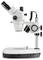 Microscope avec optique de grossissement et support réglable pour l'examen d'échantillons sur un support de table blanc.
