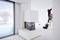 Une personne sur une échelle installe un éclairage dans un intérieur moderne. Un grand cube blanc se trouve dans la pièce, près d'une fenêtre.