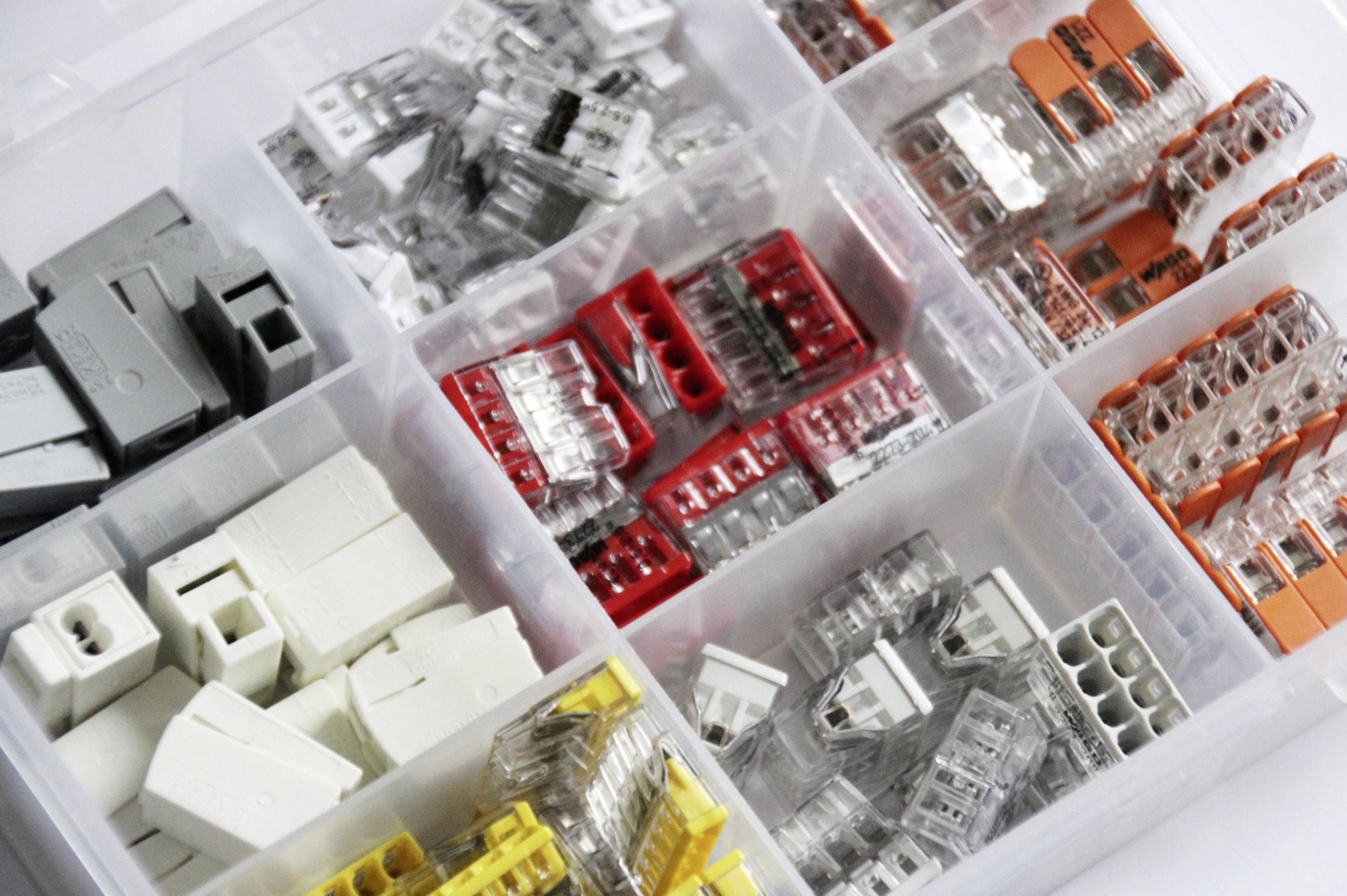 Boîte de rangement avec différents connecteurs de câbles de couleurs, rangés dans des compartiments séparés, pour l'organisation des composants électroniques.