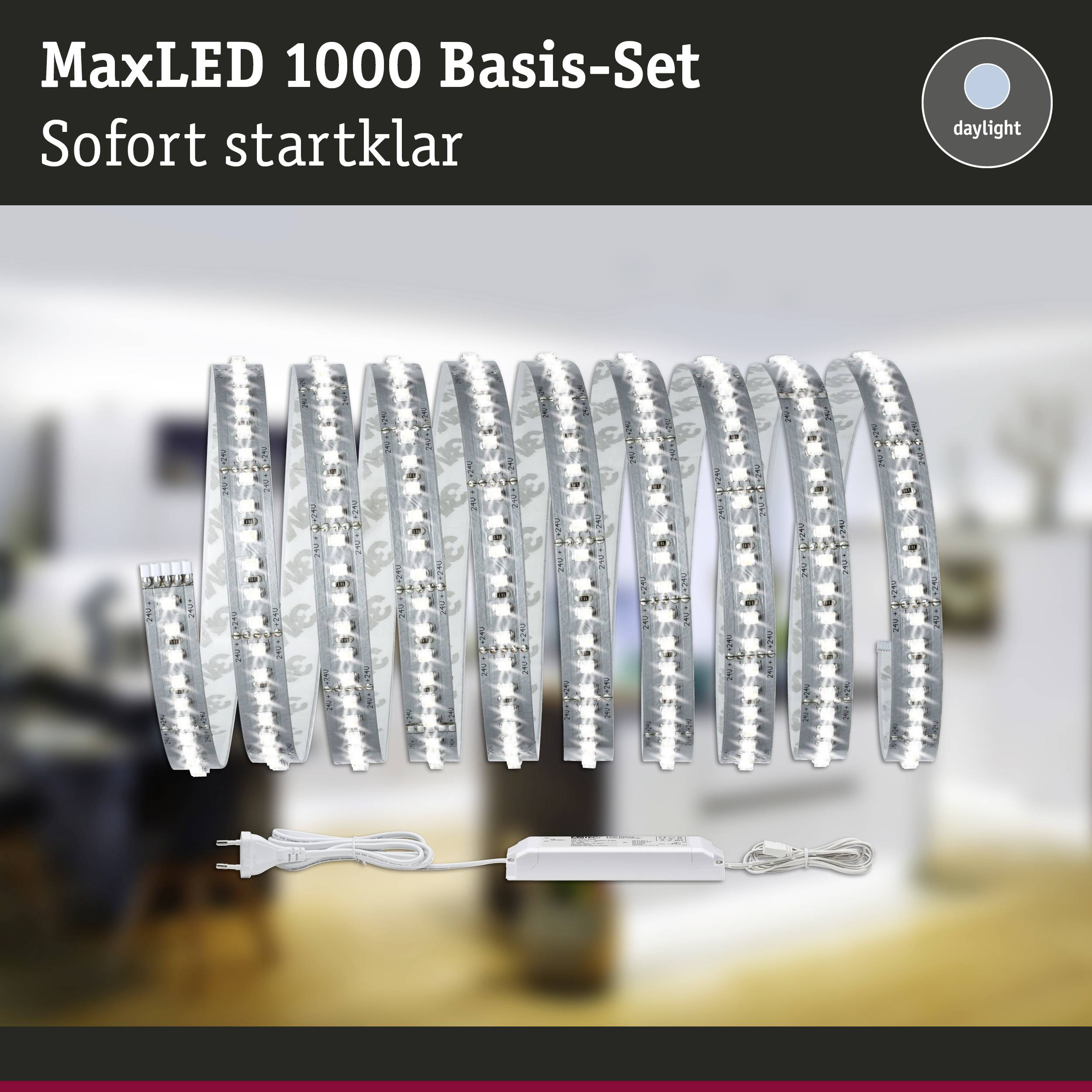 Ensemble de bande LED MaxLED 1000 avec bloc d'alimentation et télécommande en arrière-plan d'un salon flou, texte 'Prêt à l'emploi'.
