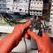 Un électricien portant des gants orange mesure la tension dans un tableau électrique. Il effectue un travail précis à l'aide d'un appareil de mesure.