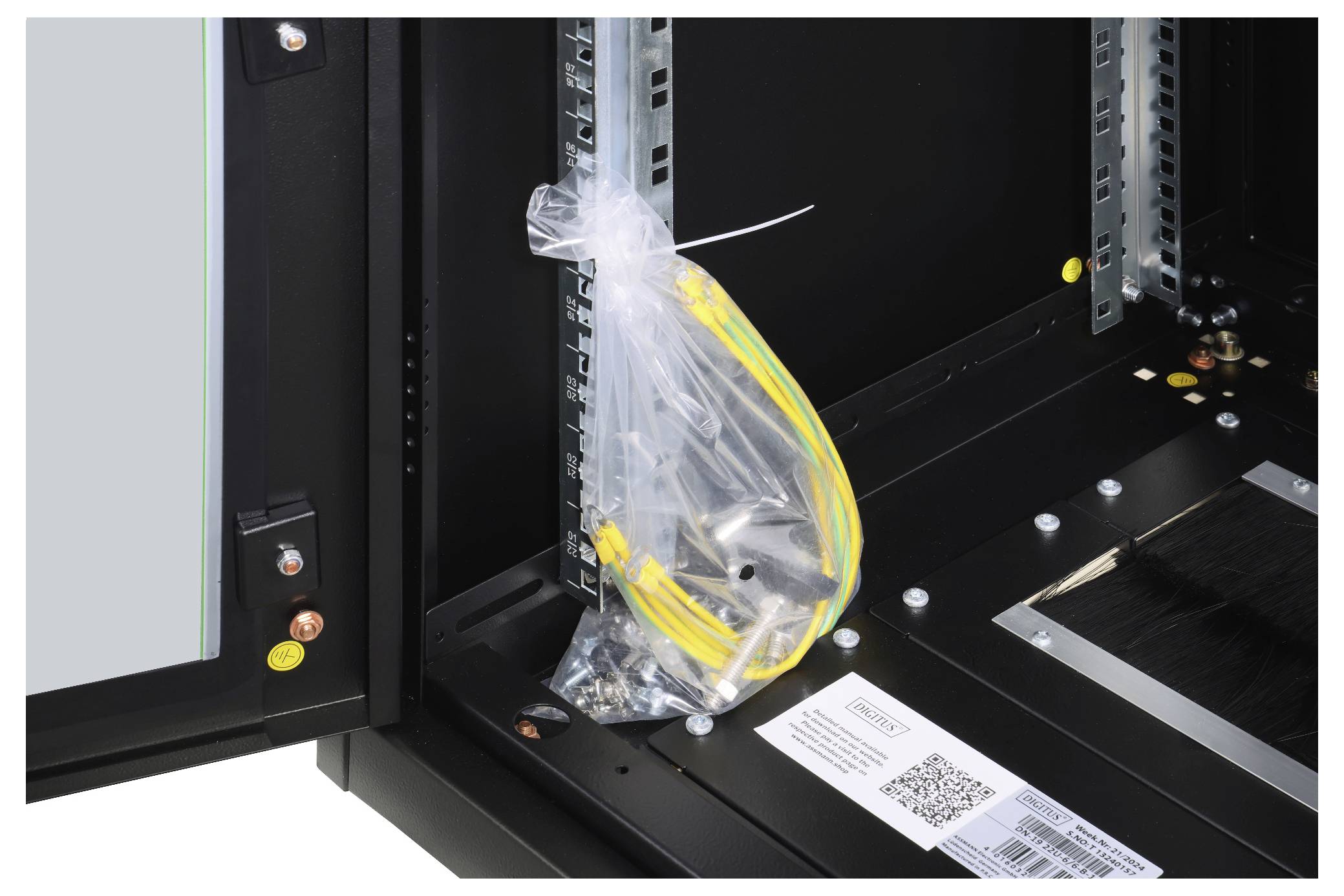 Un faisceau de câbles jaunes et vertes dans un sac en plastique transparent, fixé à l'intérieur d'un boîtier technique noir ouvert.