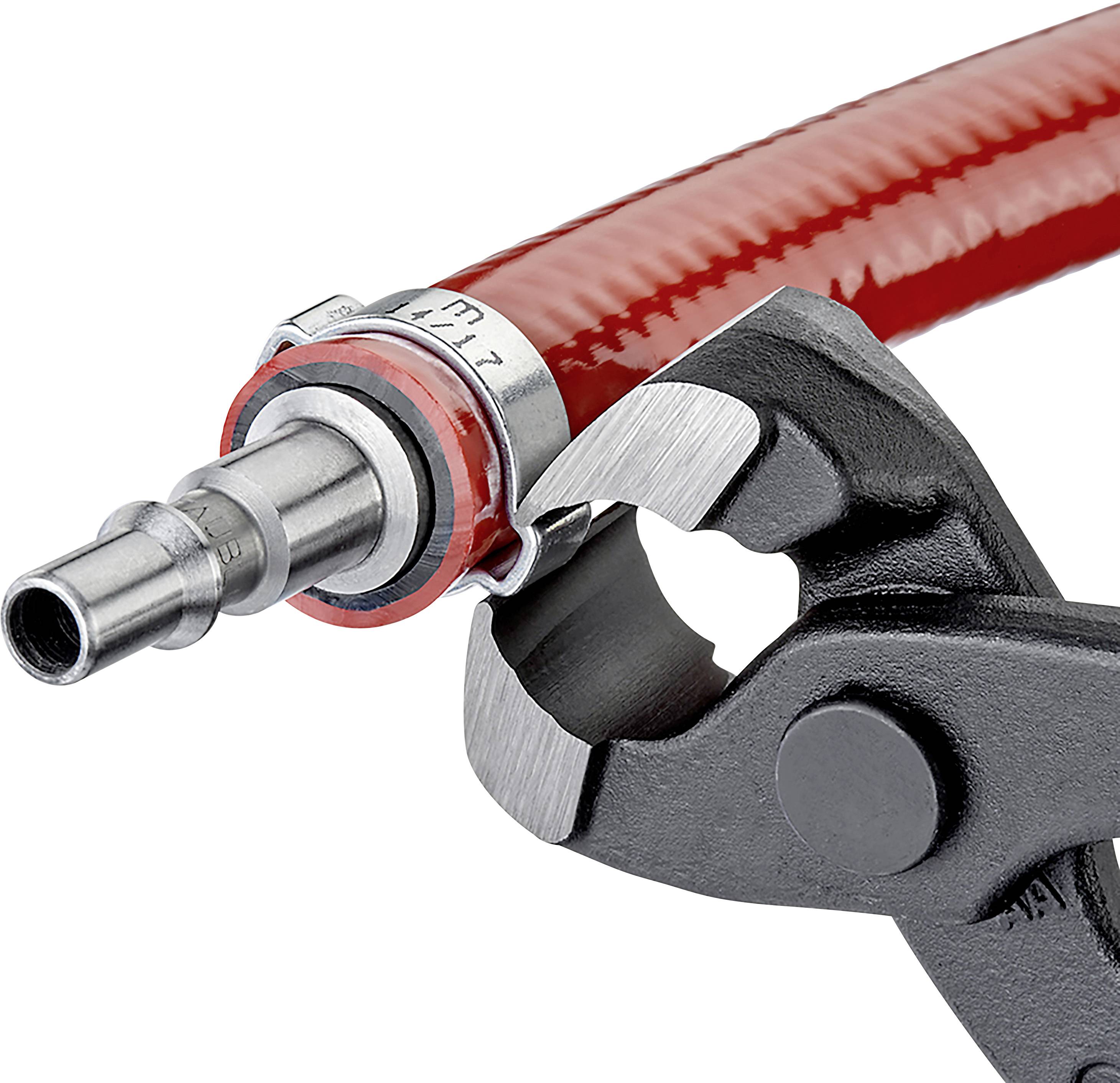 Gros plan sur une clé à molette serrant un tuyau métallique avec un tuyau rouge.