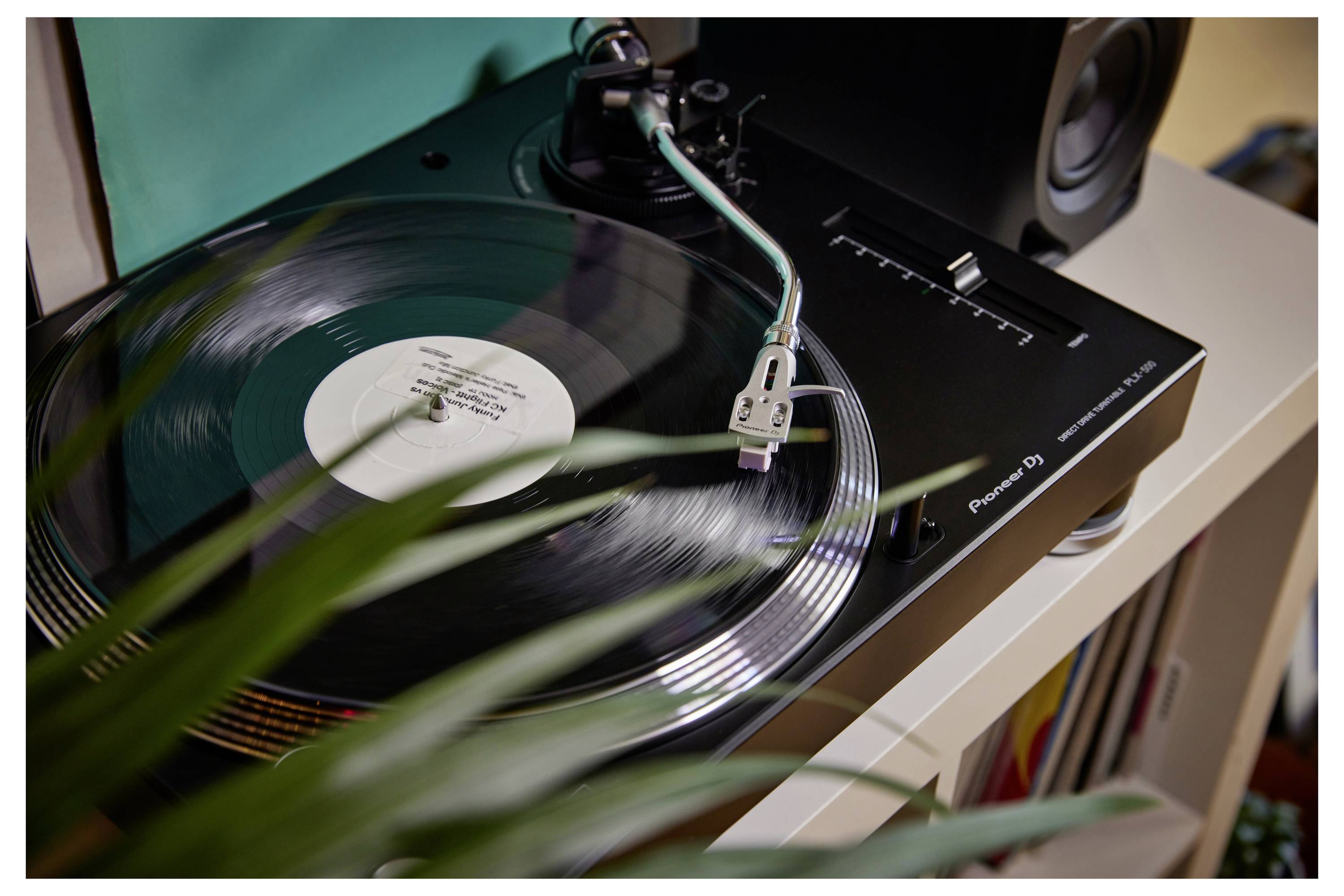 Un disque vinyle tournant sur une platine tourne-disque Pioneer DJ, avec le bras de lecture positionné sur le disque dans une configuration audio domestique.