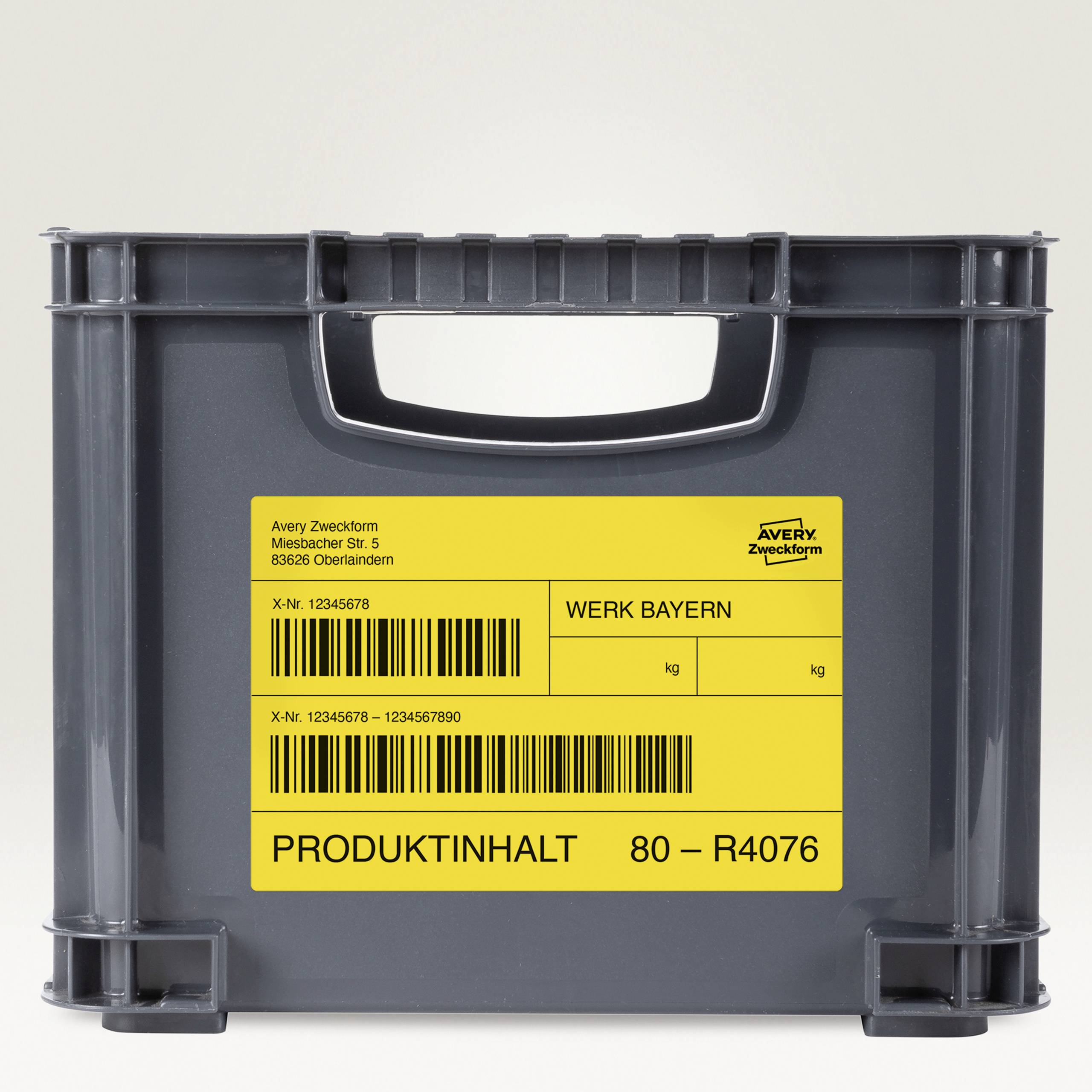 Une boîte en plastique grise avec une étiquette jaune. On peut y lire : 'Werk Bayern', suivie de codes-barres et d'un numéro de référence.