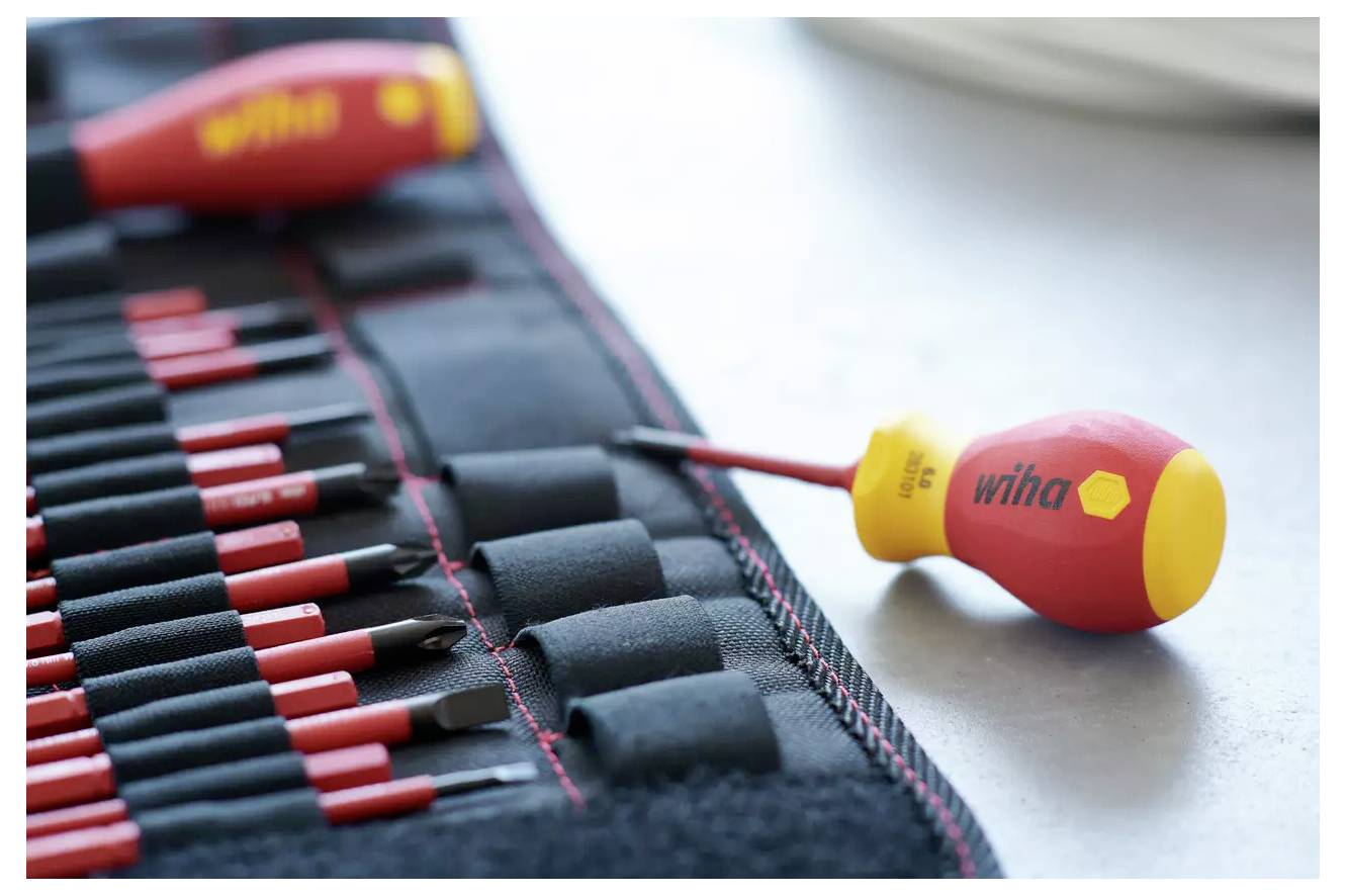 Un ensemble de tournevis colorés sur un tapis en tissu avec un mis en évidence au premier plan. Les outils sont organisés soigneusement en rangées.