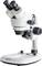Un microscope de laboratoire blanc à deux oculaires et plusieurs molettes de réglage est posé sur un socle stable.