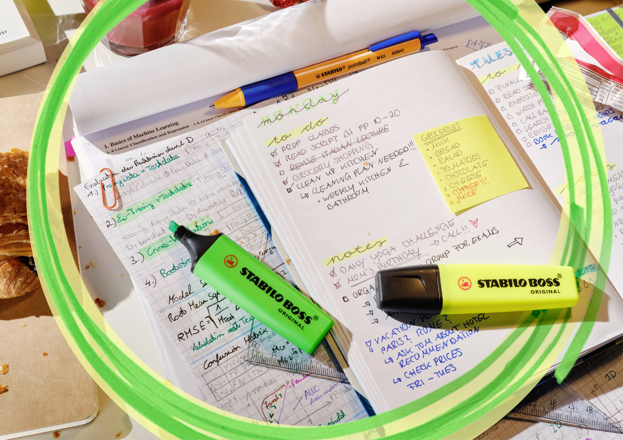 Carnet de notes avec des annotations manuscrites de différentes couleurs. Divers surligneurs et un stylo sont dispersés sur la table.