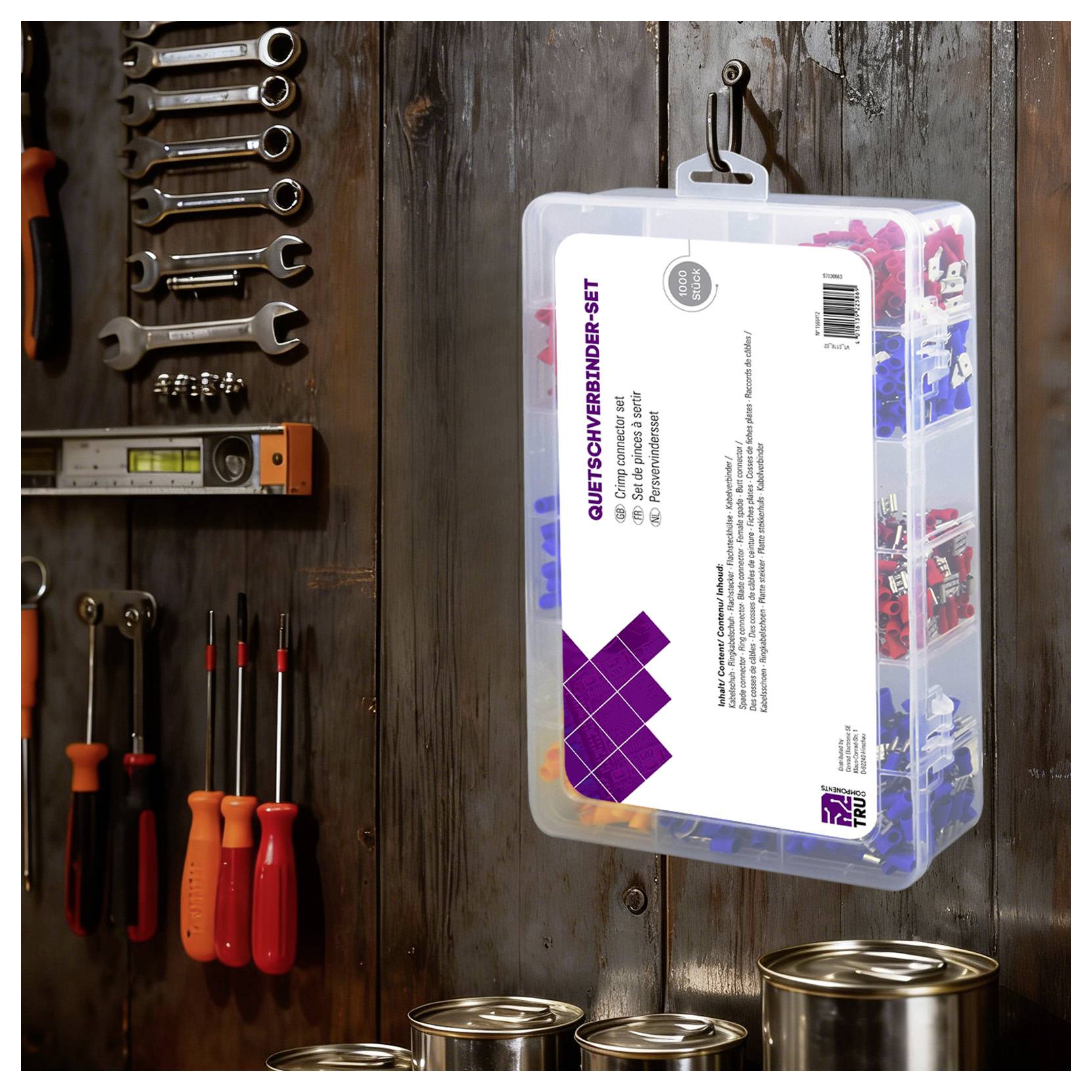 Boîte de rangement en plastique étiquetée « QUETSCHVERBINDER-SET » accrochée à un mur en bois à côté d'outils à main assortis et de pots de peinture