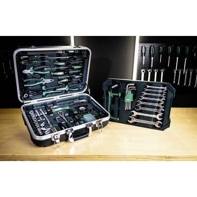 Des boîtes à outils contenant diverses clés, pinces, douilles et tournevis sont disposées sur un établi. Un panneau perforé supporte des outils supplémentaires.