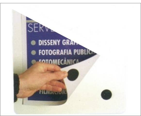 Une main tourne une page blanche, révélant un poster portant l'inscription 'Design Graphique, Photographie Publicitaire, Photomécanique'.