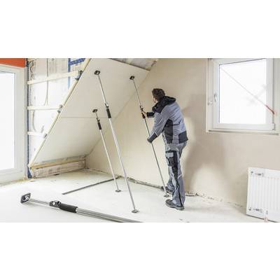 Un artisan fixe une plaque de plâtre sur un pan de toit à l'aide de supports. Une fenêtre et un radiateur sont visibles dans la pièce.