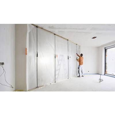Un artisan fixe un film plastique sur un mur dans une pièce vide. Le film protège contre la poussière et les salissures.