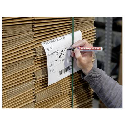 Une main étiquette une pile de feuilles de carton avec une étiquette de produit blanche indiquant les dimensions, les numéros d'article et un code-barres.
