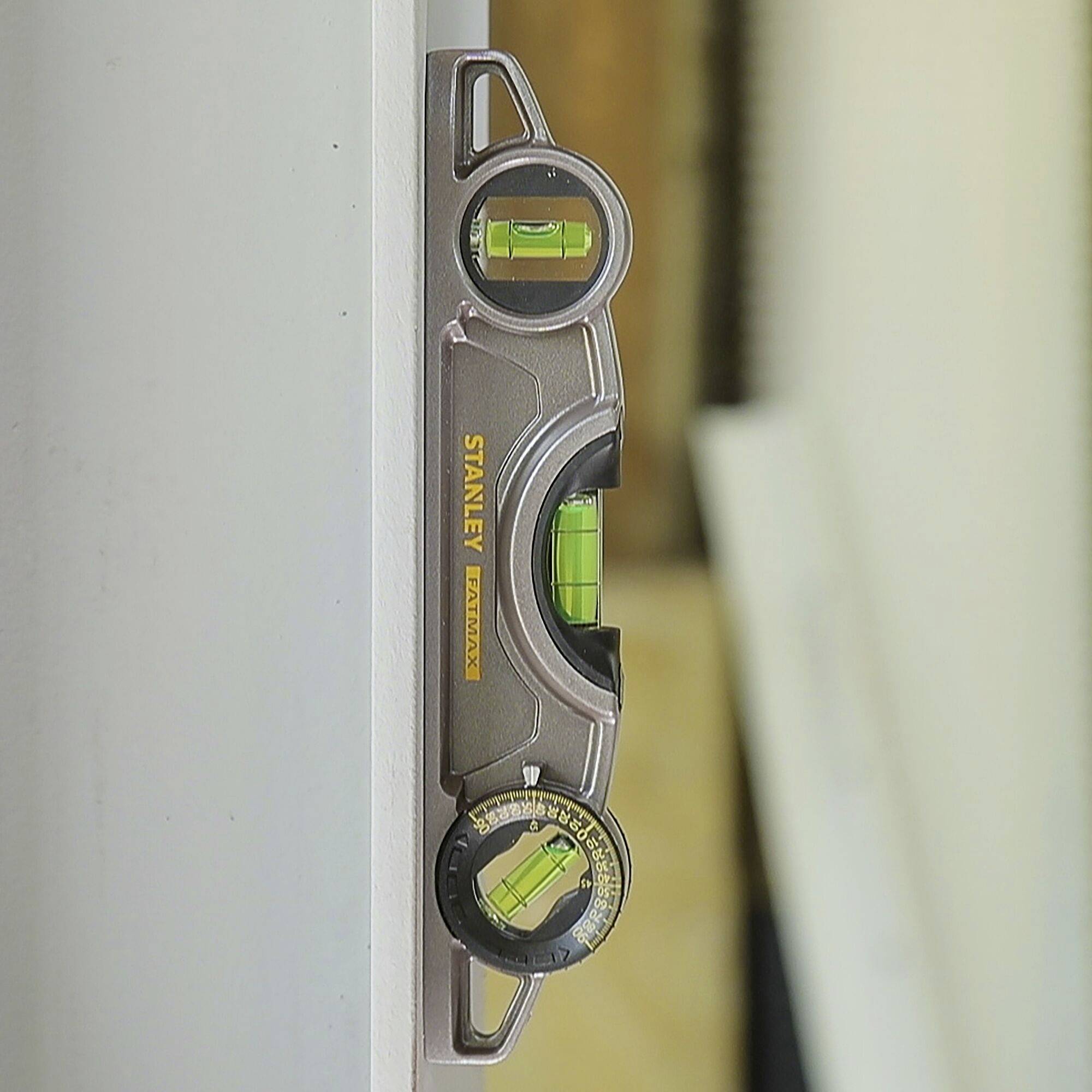 Un niveau à bulle est aligné verticalement contre un mur pour vérifier la verticalité.