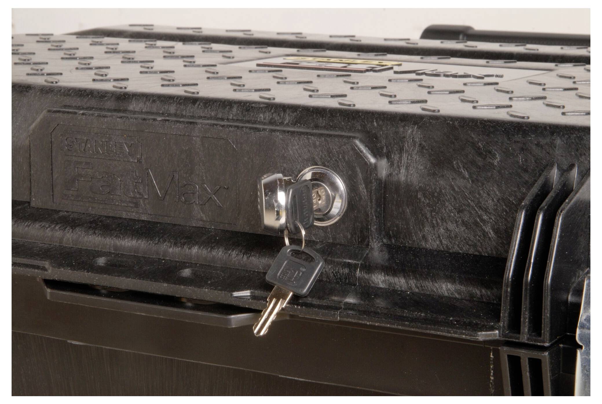 Gros plan sur une boîte à outils noire avec une clé métallique dans la serrure. Le couvercle présente une surface texturée.