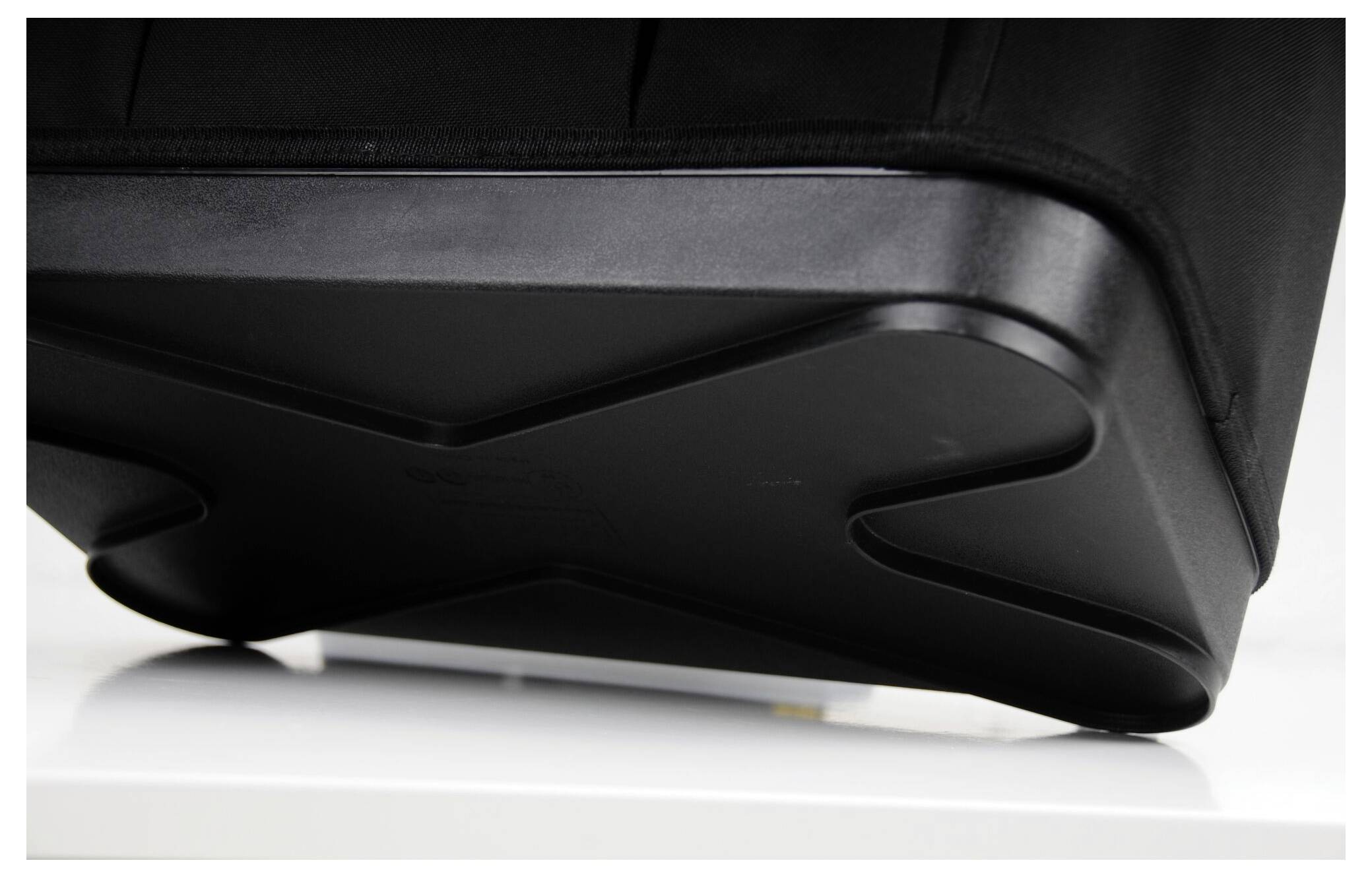 Une valise noire sur une table blanche. Le dessous de la valise présente un design en forme de X.