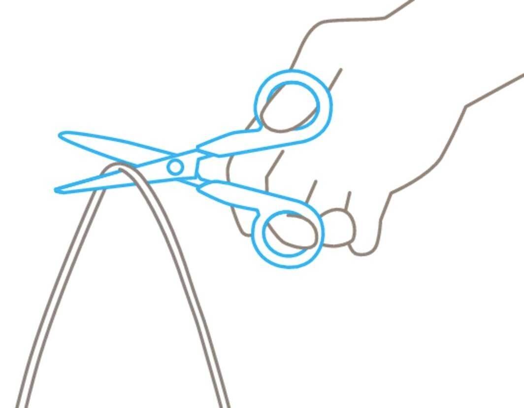 Une main tient des ciseaux et coupe un morceau de ficelle.