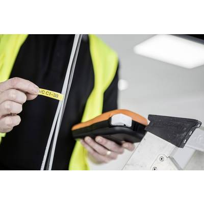 Une personne se tient sur une échelle, tenant un appareil de mesure et une étiquette portant l'inscription 'VC C1-3B'. Concentrée sur un mesurage précis.