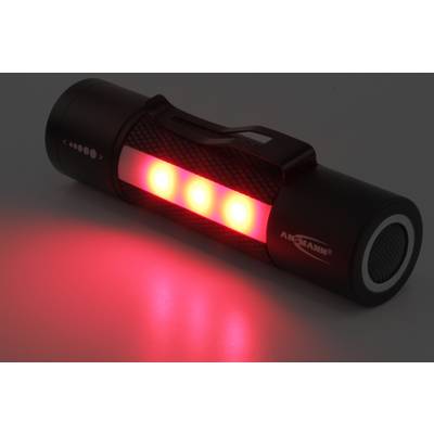 Une lampe de poche noire brille avec trois LED rouges dans l'obscurité.