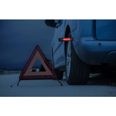 Une voiture bleue avec un pneu crevé est garée sur le bord de la route. Un triangle de signalisation aux bords réfléchissants est placé devant la voiture.