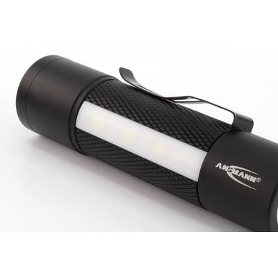 Lampe de poche noire avec poignée texturée et clip, zone lumineuse blanche, nom de marque 'ANSMANN' visible.