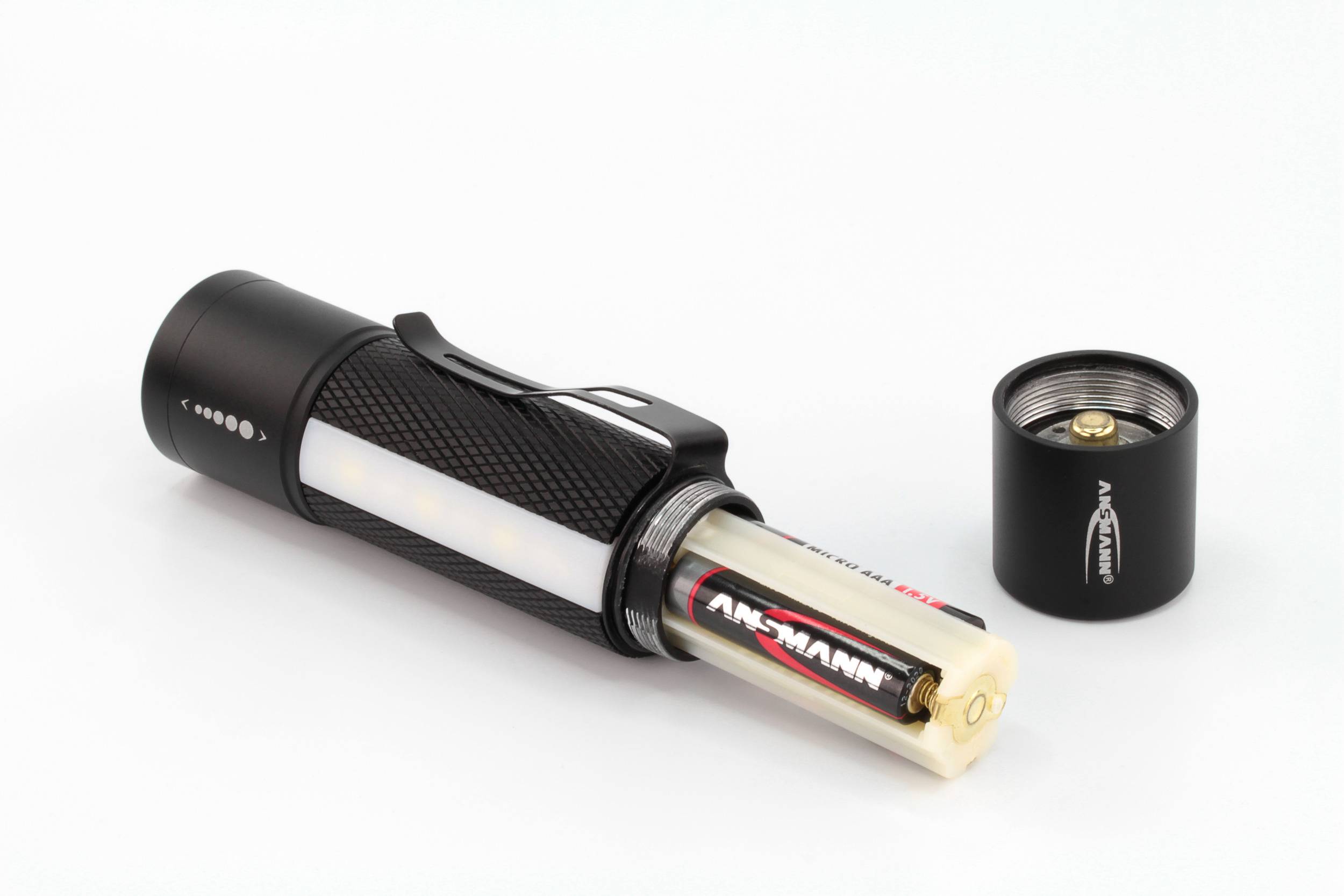 Une lampe de poche noire avec son couvercle de compartiment à piles retiré montre une pile AA insérée. Le compartiment à piles est partiellement visible.