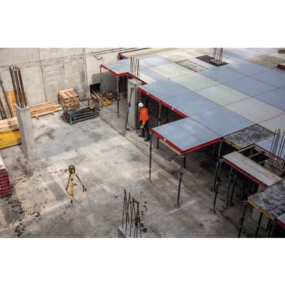 'Ouvriers de construction portant des vêtements de protection orange sur un chantier. Des dalles de plafond sont étayées et des équipements de construction sont visibles.'
