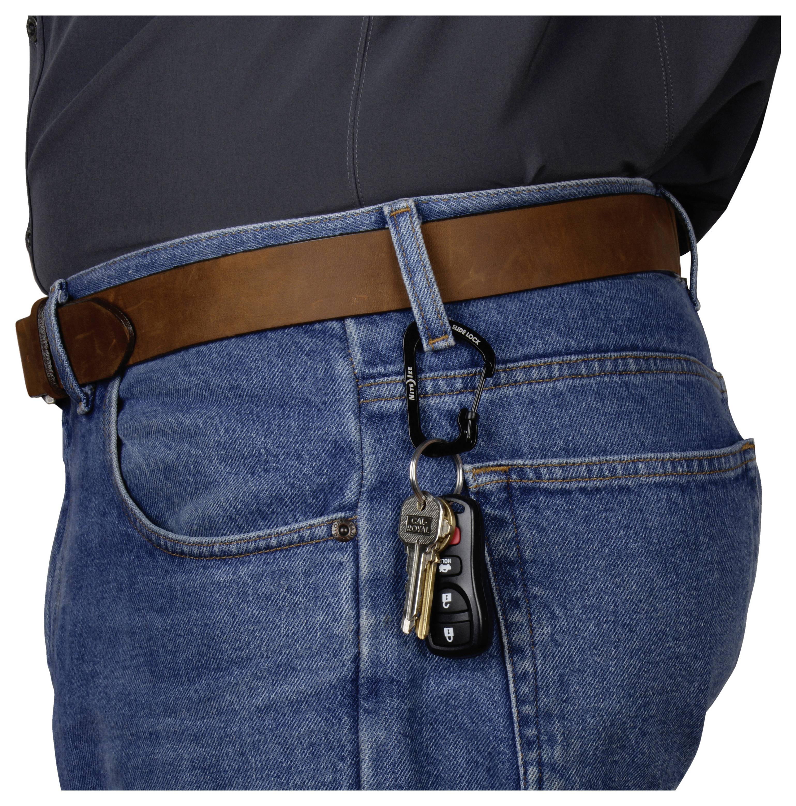 Des clés et un porte-clés de voiture suspendus à une boucle de jean, illustrant une méthode de transport pratique.