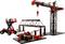 Coffret de construction comprenant un modèle de grue, une plateforme élévatrice, un pont et un établi en pièces plastiques rouges et noires. Idéal pour les passionnés de technique.