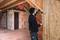 Un ouvrier vérifie l'alignement vertical d'un mur en bois dans un bâtiment en construction à l'aide d'un niveau à bulle.