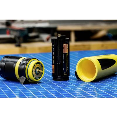 Appareil électronique simple avec compartiments de batterie ouverts sur une table à motifs bleus, prêt pour l'entretien ou le remplacement des piles.