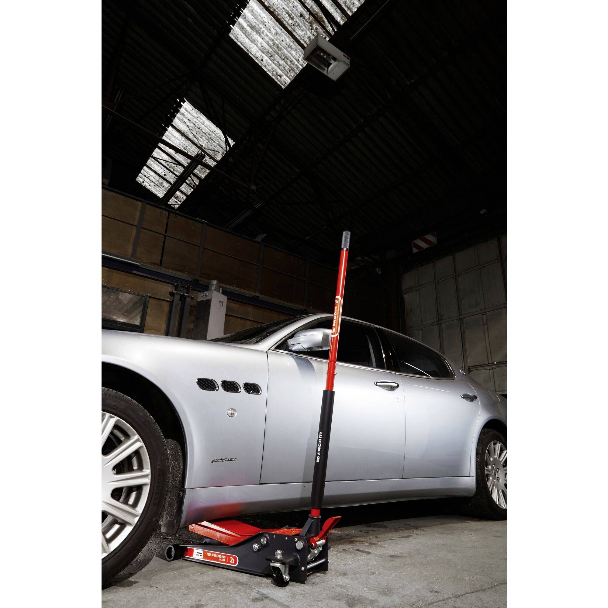 'La voiture dans le garage est soulevée avec un cric hydraulique.'