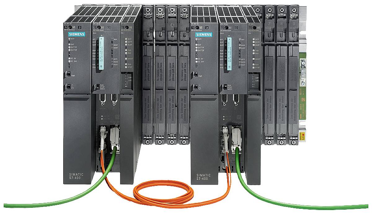 Trois boîtiers de commande industriels noirs avec des câbles de connexion en vert et orange, portant l'inscription 'SIMATIC S7-400'