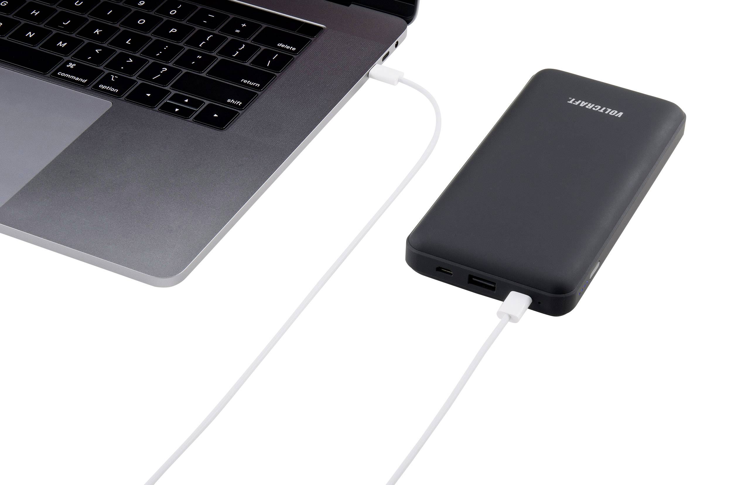 Un ordinateur portable est connecté à une batterie externe noire via un câble blanc, illustrant l'alimentation mobile.