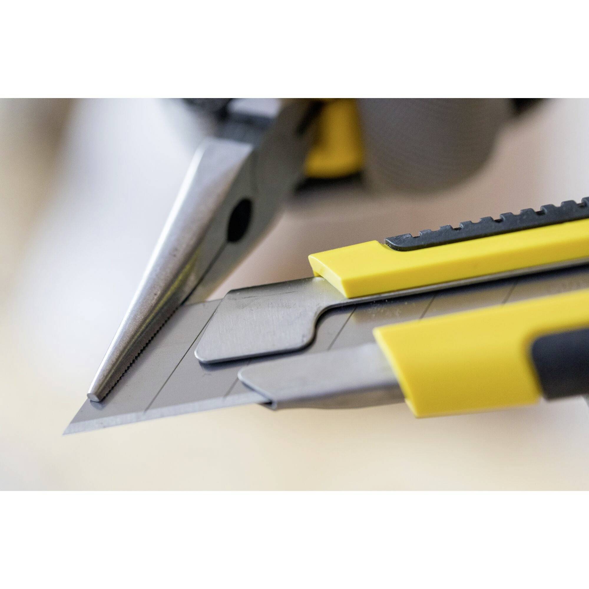 Un coupe-câble jaune et une pince sont posés sur la table, nets et bien mis au point, avec un arrière-plan flou. Ils symbolisent les outils et le travail artisanal.