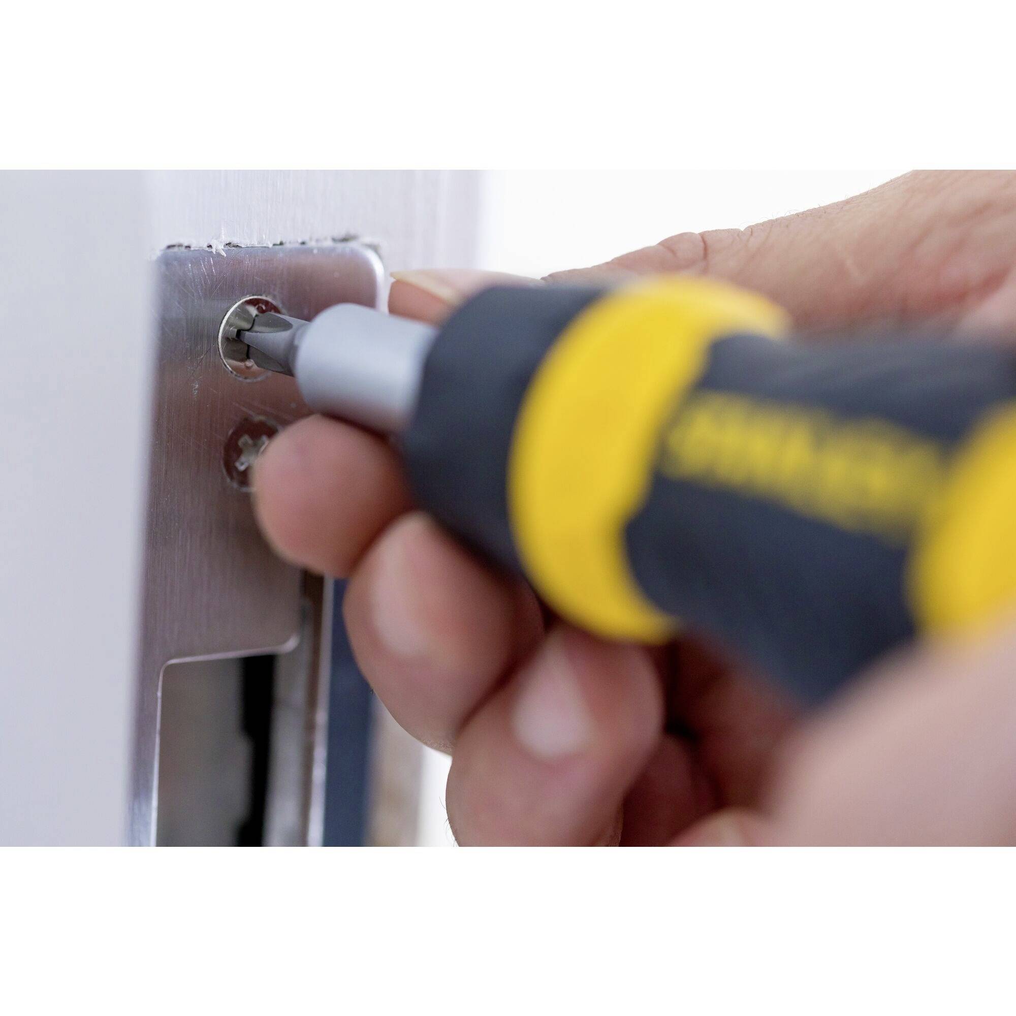 Une personne répare une porte avec un tournevis qui est inséré dans une serrure.