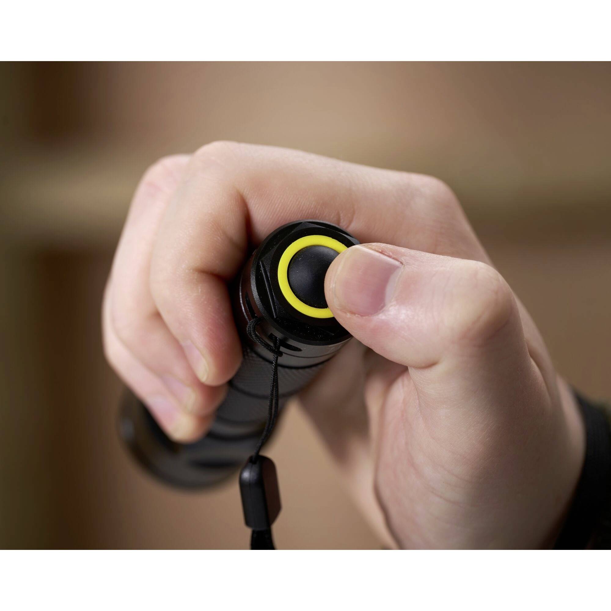 Une main tient un appareil avec un bouton sur lequel on appuie avec le pouce ; il pourrait s'agir d'une lampe de poche.