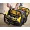 Une main retire un tournevis d'un sac à outils noir et jaune rempli de divers outils.