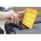 Une personne trie des vis et des chevilles dans un récipient jaune posé sur une boîte à outils. Les mains sont au premier plan, l'accent étant mis sur l'organisation.