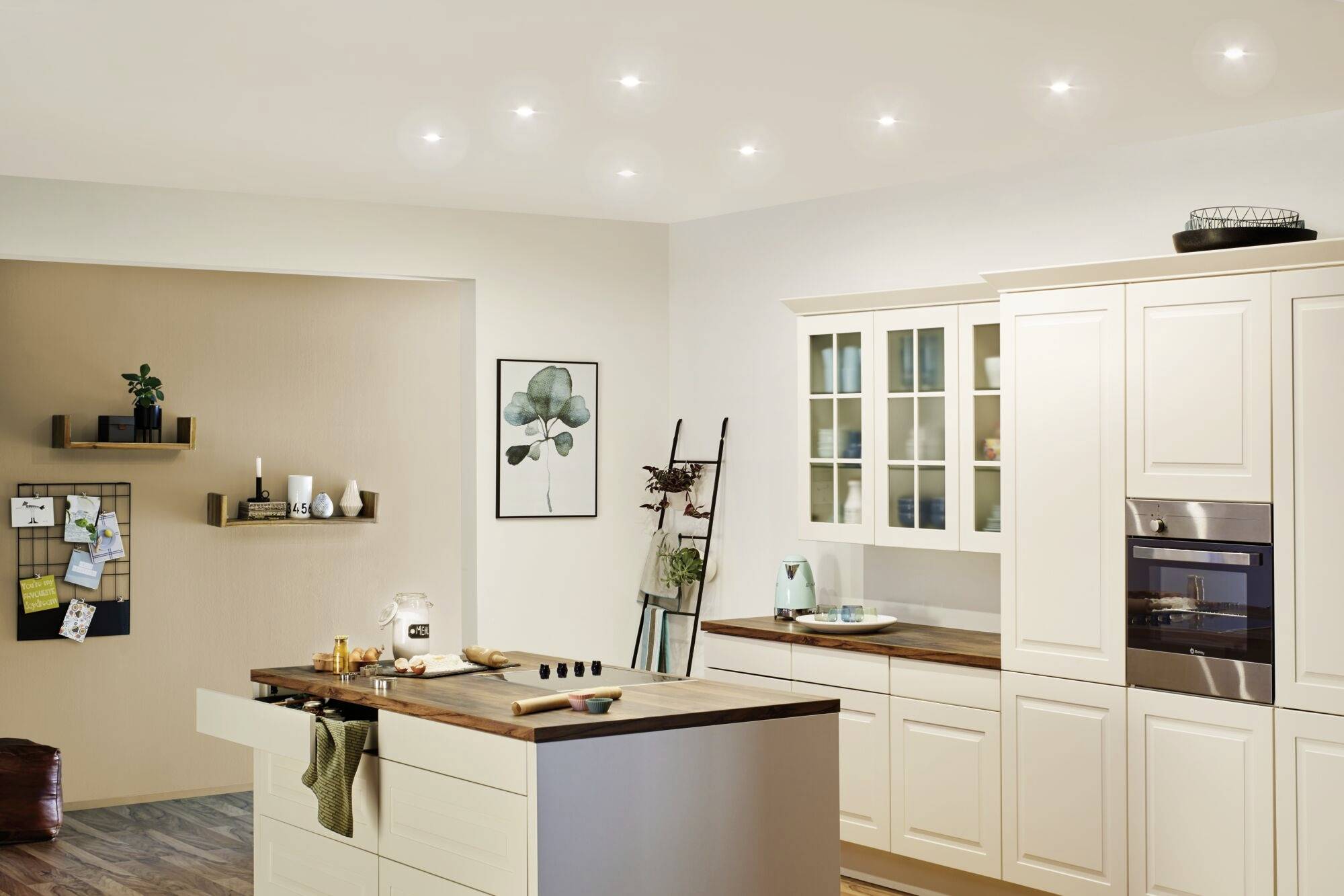 Cuisine lumineuse et moderne avec façade d'armoires blanches, plans de travail en bois, îlot central et éléments décoratifs muraux.