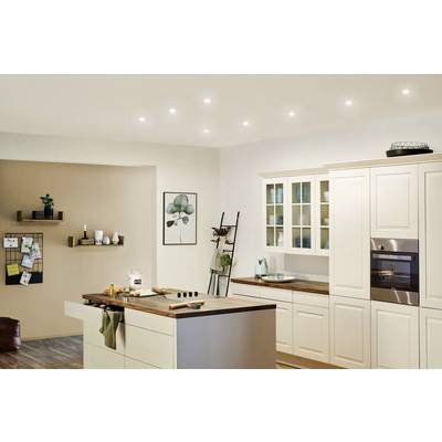 Cuisine moderne avec armoire blanche, four encastré et îlot central. L'éclairage est discret, les décorations sont minimalistes.