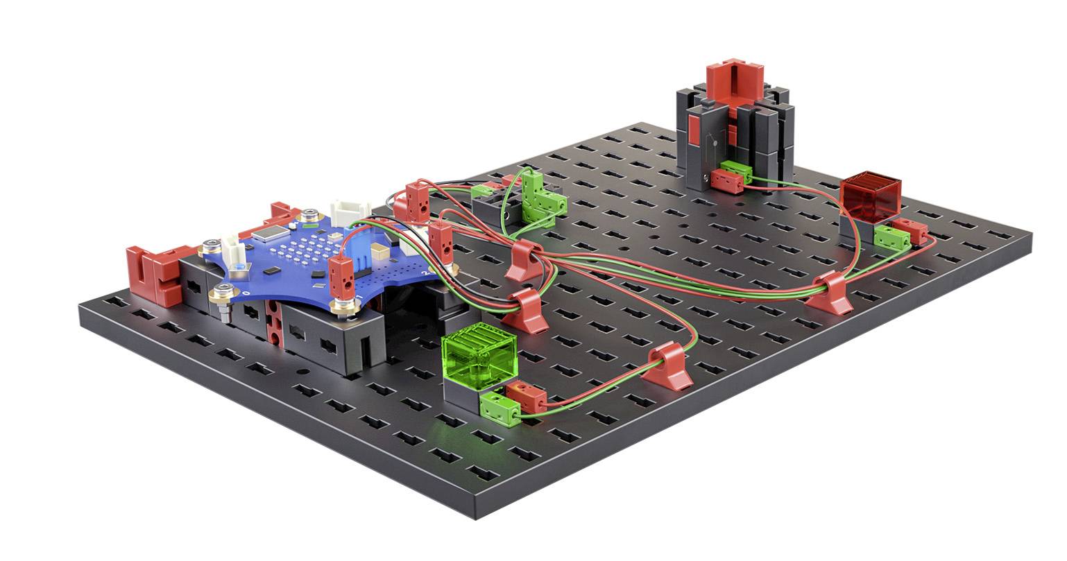'Kit électronique sur une plaque perforée, composé de modules enfichables rouges et verts, reliés par des fils colorés.'