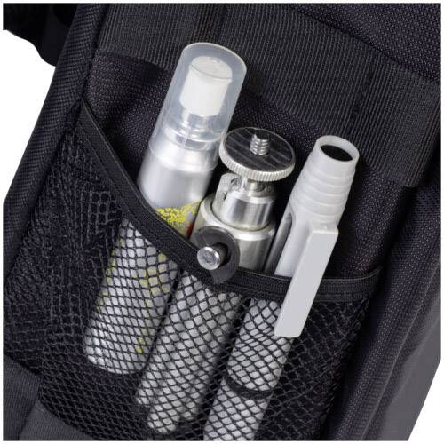 Trois flacons pulvérisateurs et un stylo dans une poche en filet d'un sac à dos noir, photographiés de près.