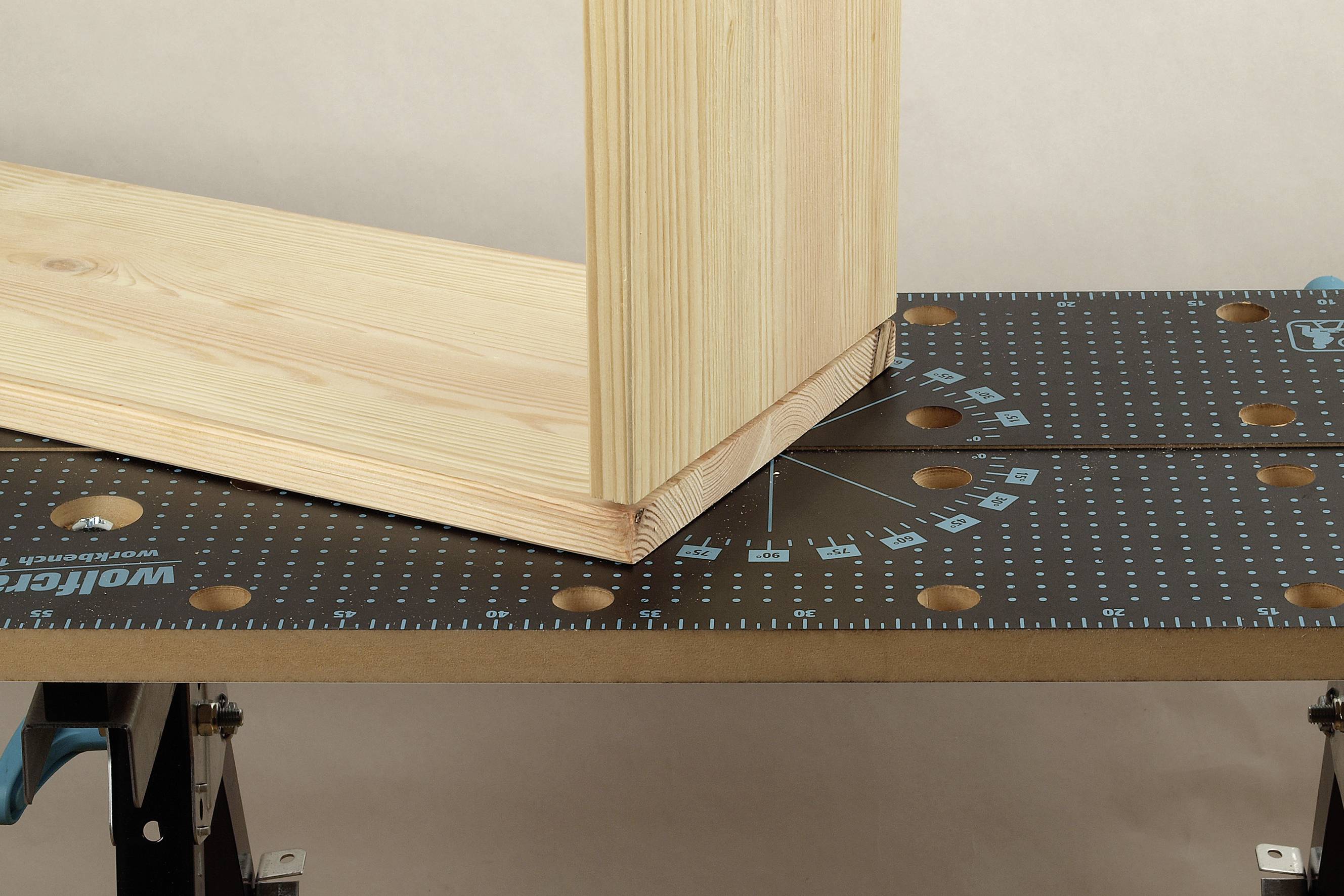 Une planche de bois est montée sur une table de travail, l'angle étant vérifié à l'aide d'un rapporteur.