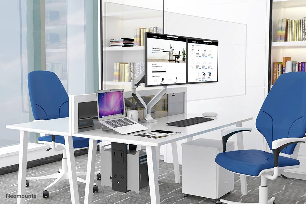 Bureau moderne avec deux chaises bleues, des bureaux blancs, plusieurs écrans et des étagères à livres en arrière-plan.