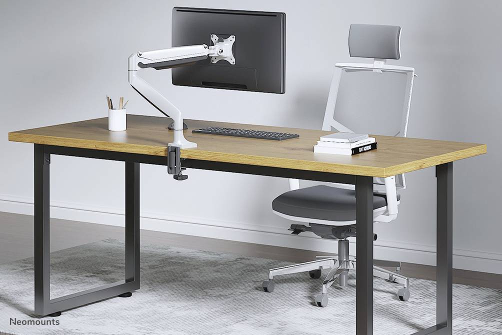 Un bureau moderne avec un plateau en bois, un support d'écran et une chaise ergonomique sur un tapis. Des fournitures de bureau sont disposées sur le bureau.