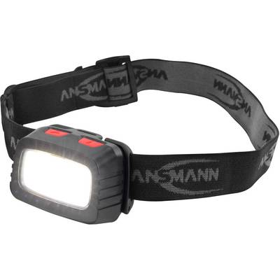 Une lampe frontale noire avec un bandeau gris et un interrupteur rouge sur le dessus, qui éclaire intensément. Sur le bandeau, on peut lire 'ANSMANN'.