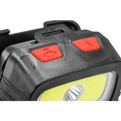 Gros plan d'un lampe frontale noir avec deux boutons rouges : Un bouton avec un symbole de lumière, l'autre avec un symbole de flèche.